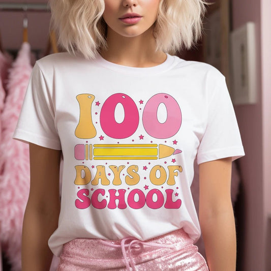 A person wearing a white "100 Days of School" t-shirt featuring a retro design and colorful pencil graphic, showcasing cute teacher t-shirts. Shop now at TeachingTeez.com!