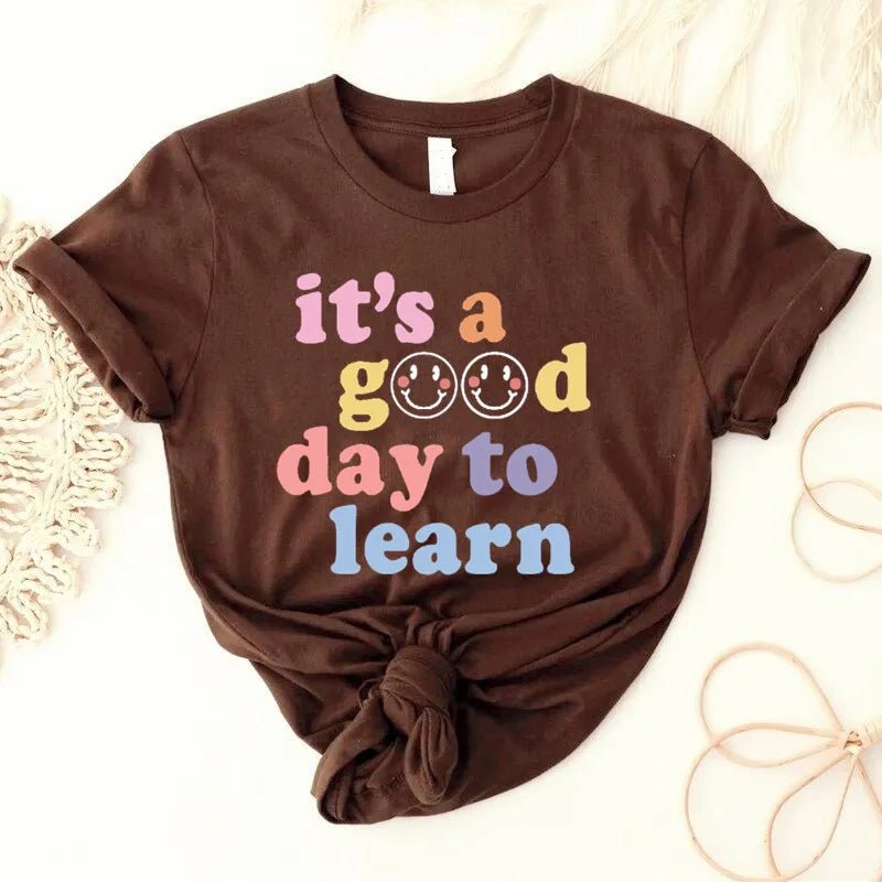 Coffee shirt Flat lay of the "It's a Good Day to Learn" t-shirt featuring colorful, playful lettering with smiley faces in the "O"s of "Good," crafted from soft fabric for comfort—shop today and spread positivity!