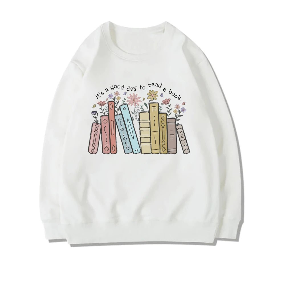 White sweatshirt with the phrase "It's a Good Day to Read a Book," featuring pastel-colored books and flowers growing from the pages. This cute book lover sweatshirt is perfect for teachers or anyone who wants to celebrate reading. Find this literary-inspired sweatshirt at TeachingTeez.com.