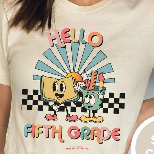 White t-shirt with a retro "Hello Fifth Grade" design, featuring a cheerful open book and a cup of classroom supplies with friendly faces. A checkered pattern and rising sun add vintage flair, creating a welcoming and playful vibe perfect for fifth-grade teachers. This cute teacher t-shirt is ideal for celebrating the start of the school year with style and positivity. Available at TeachingTeez.com.