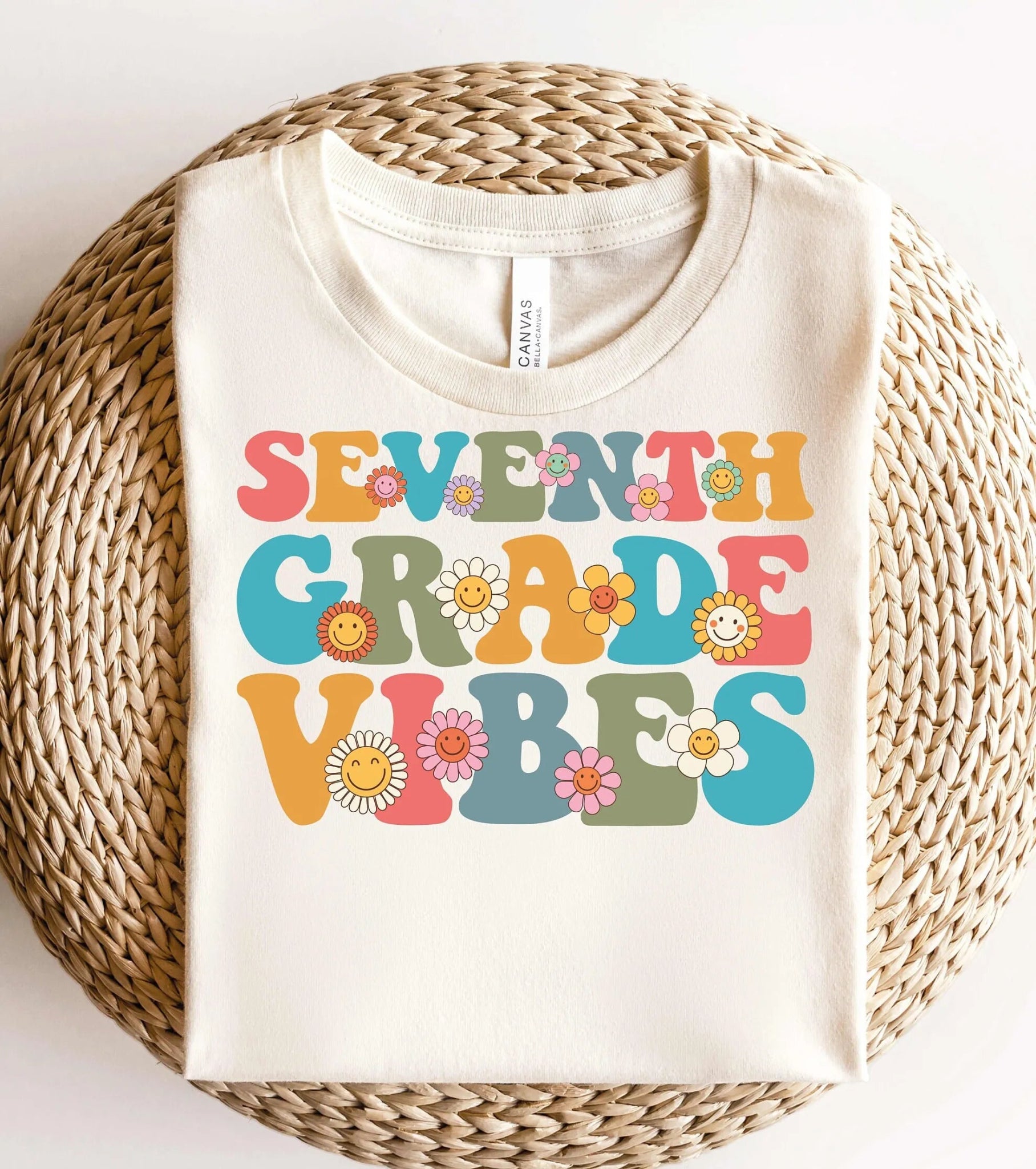 Alt Text: "Seventh Grade Vibes" t-shirt from TeachingTeez.com, featuring a retro design with colorful letters spelling "Seventh Grade Vibes." Each letter is accented by cheerful flowers with smiley faces in the center, creating a playful and positive vibe ideal for seventh-grade teachers.