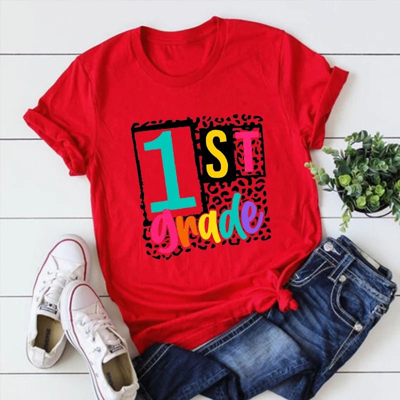 A red "1st Grade" T-Shirt from TeachingTeez.com, featuring "1st" in bold black boxes, vibrant "Grade" text, and a fun leopard print pattern. Great for first-grade teachers wanting to stand out. Get this colorful t-shirt at TeachingTeez.com!